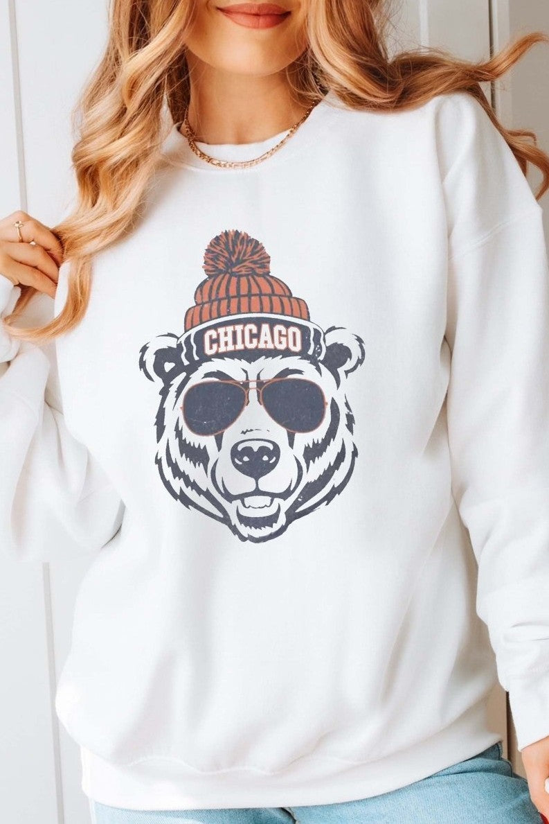 Person wearing a white sweatshirt with a bear with a beanie graphic and 'Chicago' text team Chicago Bears