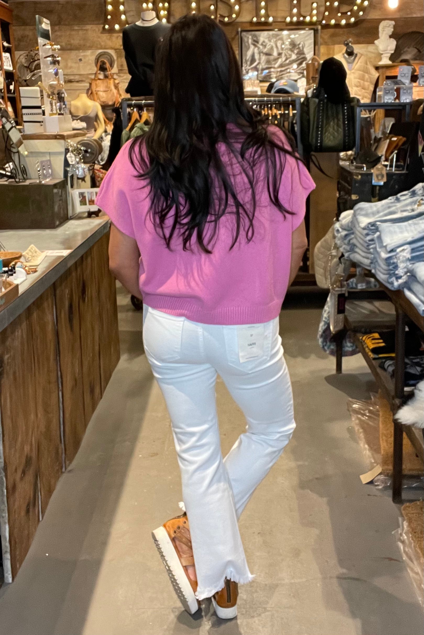 Model in pink top and white skinny jeans - back view