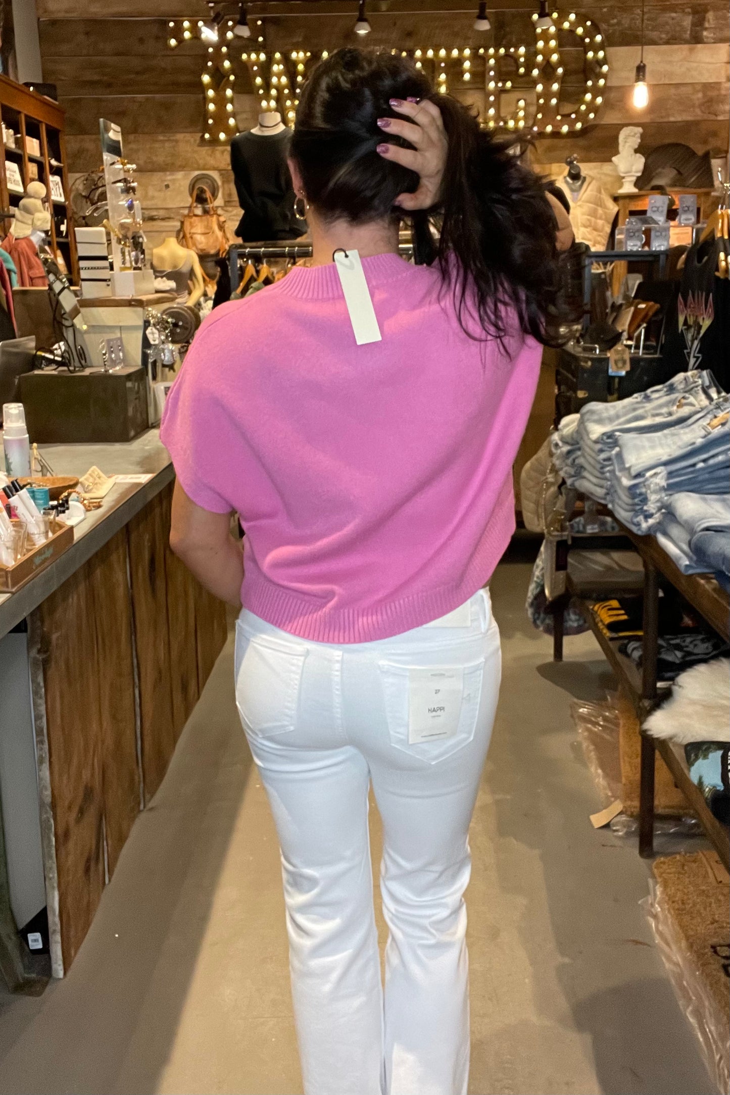 Model in pink top and white skinny jeans - back view