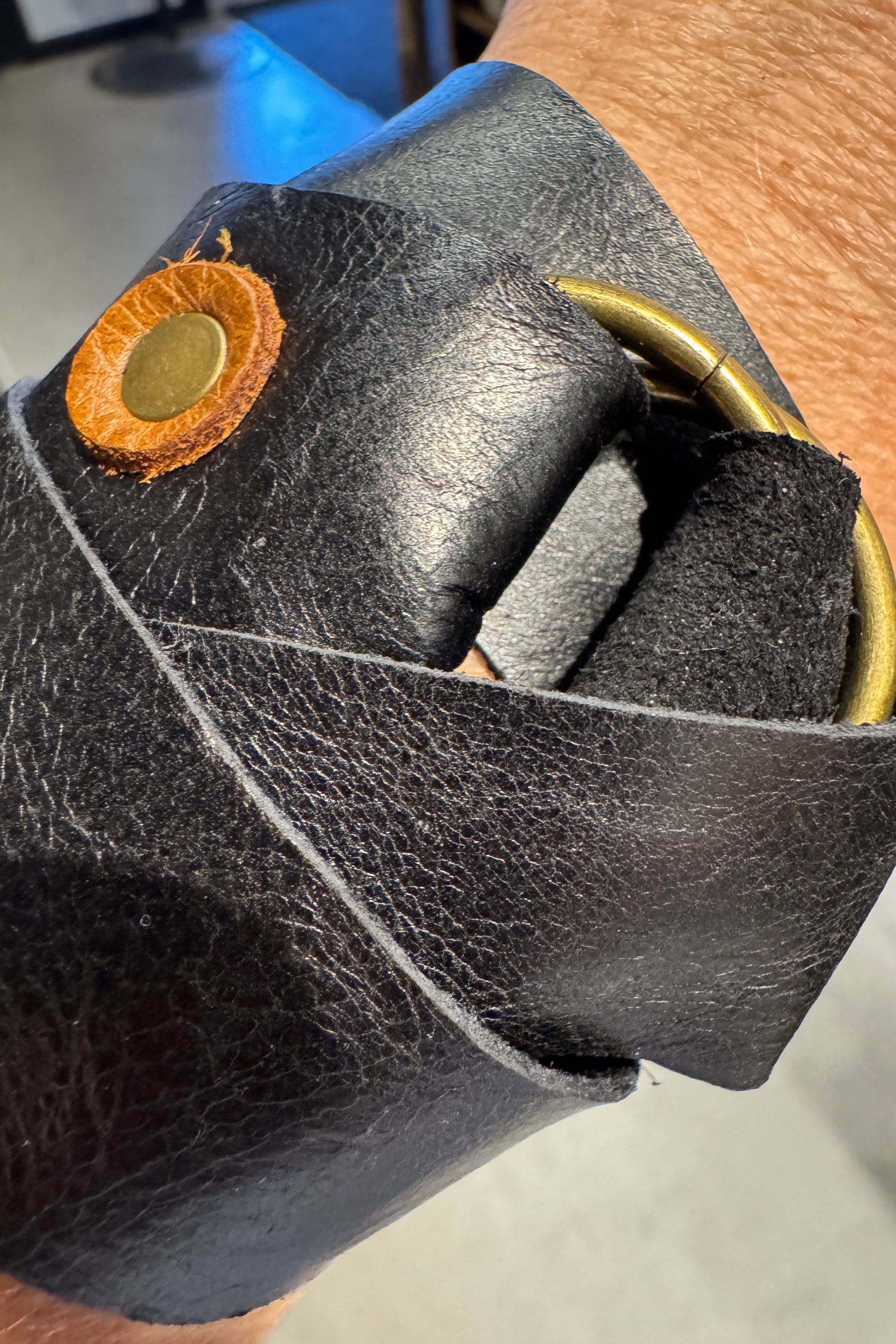 Close-up of a black leather glove with a gold button on a blurred background