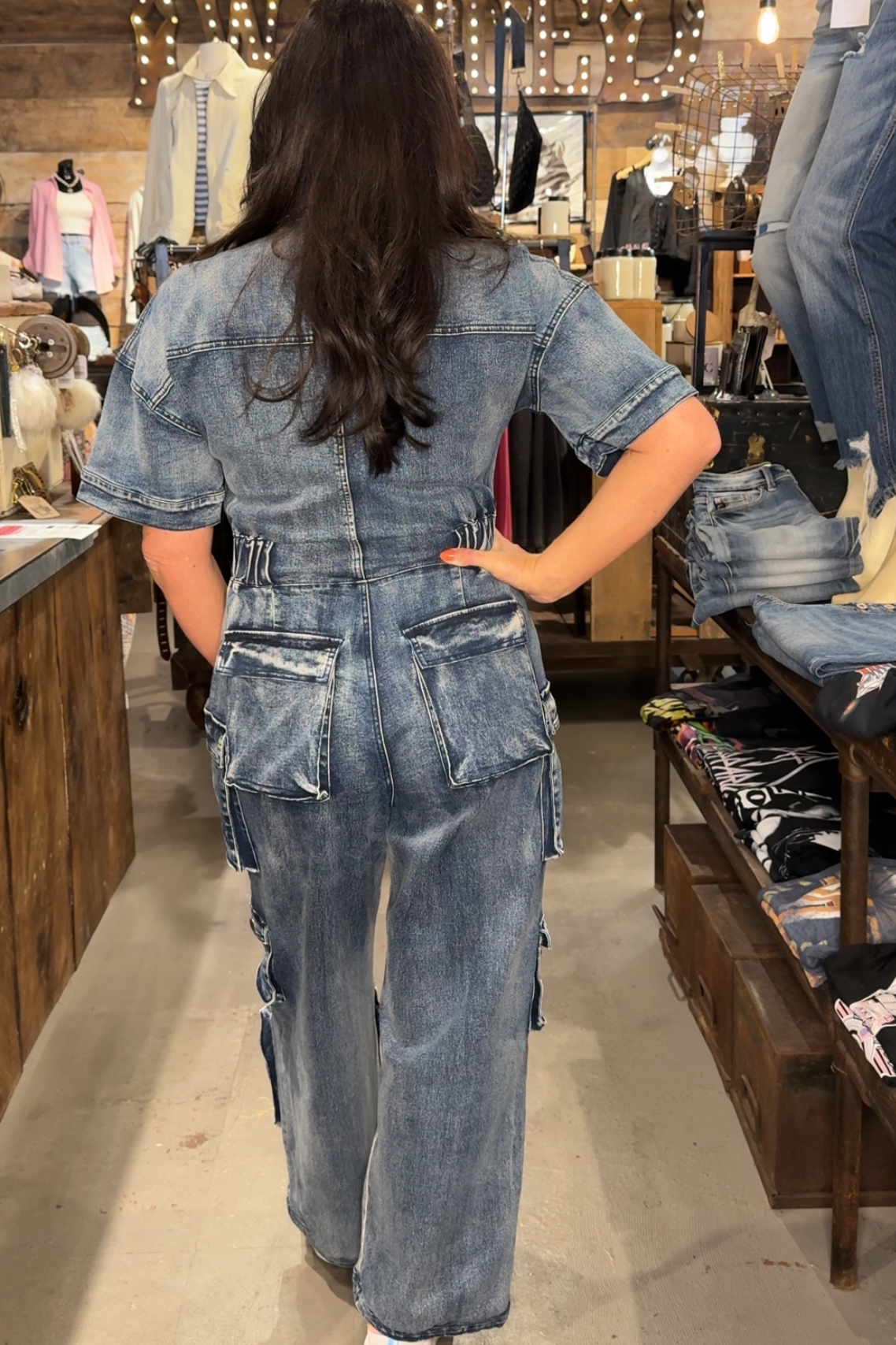 woman wearing a denim cargo jumpsuit in a store setting