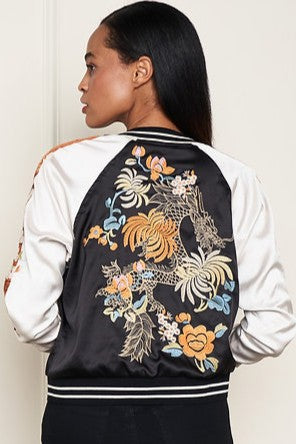 Woman wearing a black and white satin embroidered reversable jacket