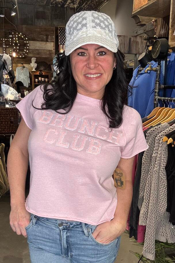 Model wearing pink short sleeve top that says, "brunch club"
