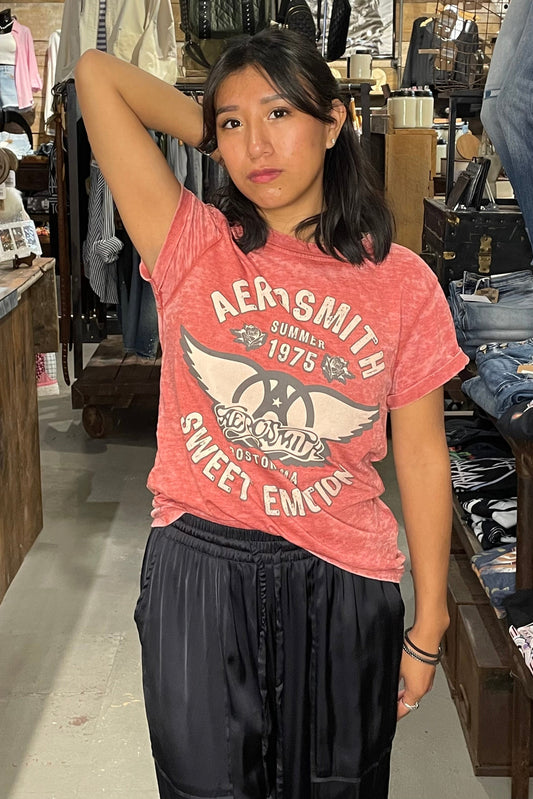 Woman wearing a red 'Aerosmith' t-shirt in a clothing store.