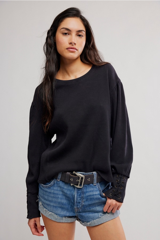 Woman wearing a black long sleeve top with laced cuffs