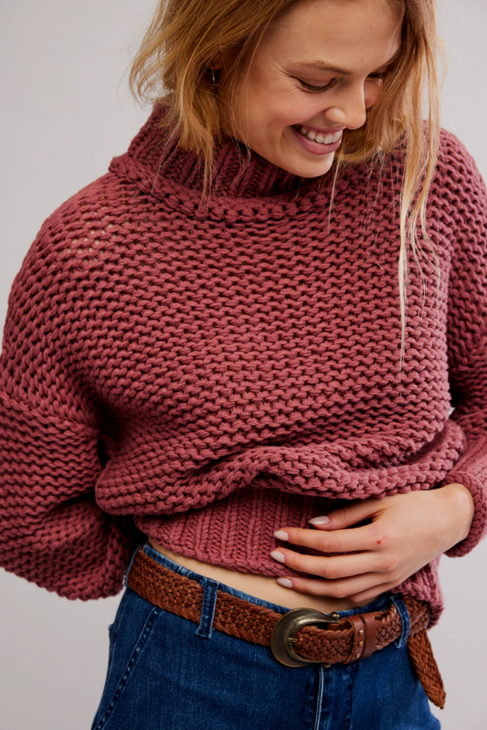 Woman wearing a rose cranberry colored chunky knit sweater with mock neck
