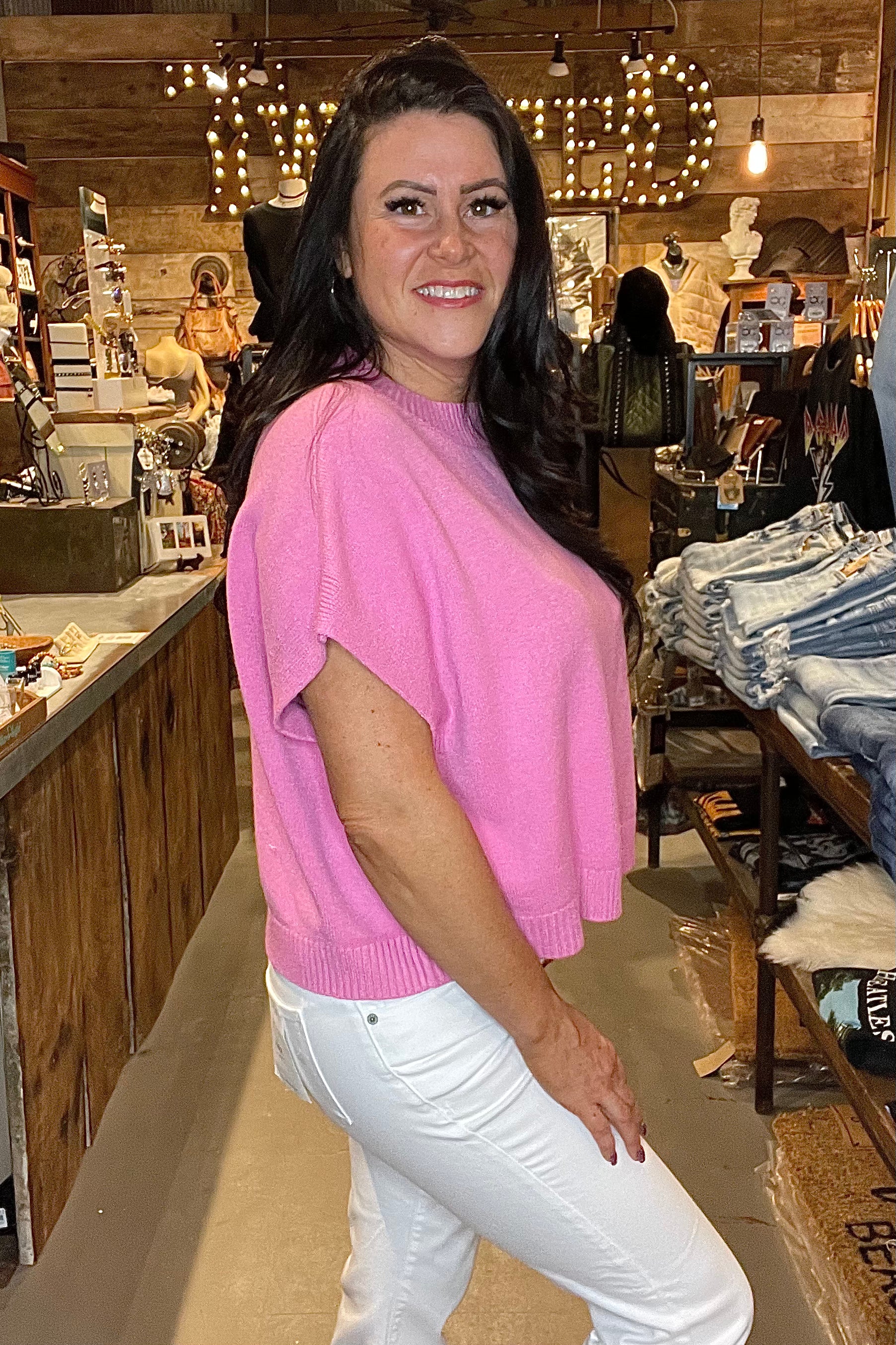 Model in pink top and white skinny jeans - side view