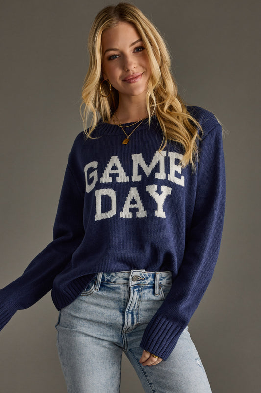 Woman wearing a navy sweater with 'GAME DAY' text on a gray background
