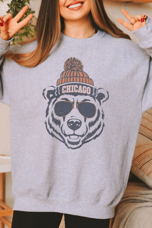 Person wearing a gray sweatshirt with a bear with a beanie graphic and 'Chicago' text team Chicago Bears