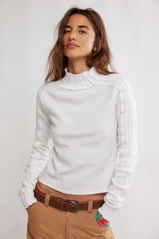 Woman wearing a white long-sleeve cable knit sweater top 