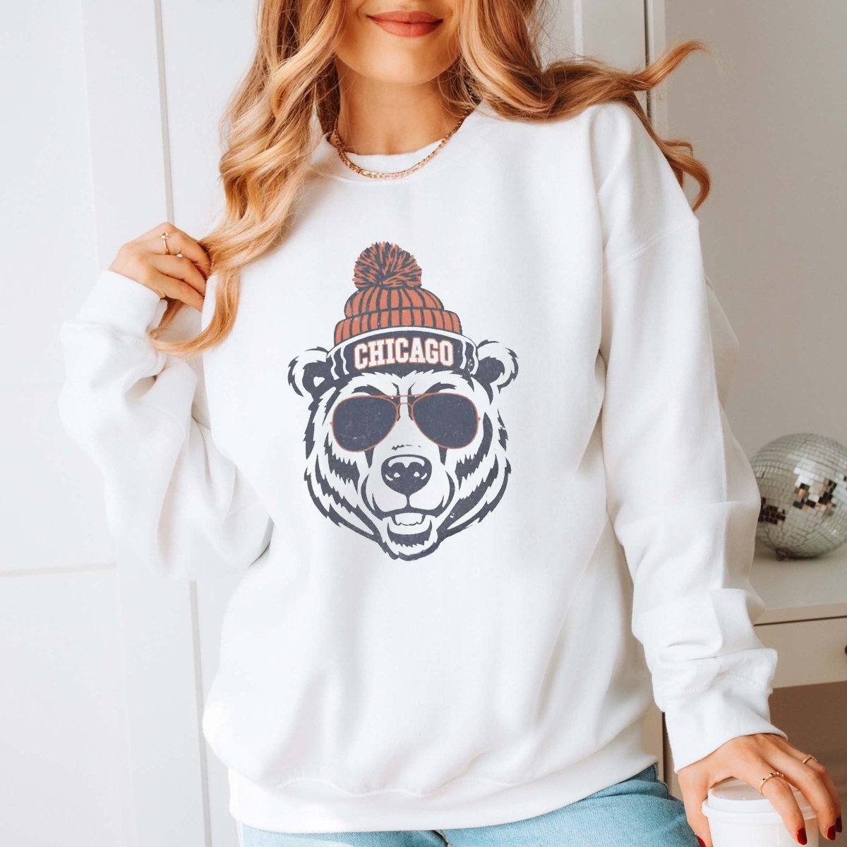 Person wearing a white sweatshirt with a bear with a beanie graphic and 'Chicago' text team Chicago Bears