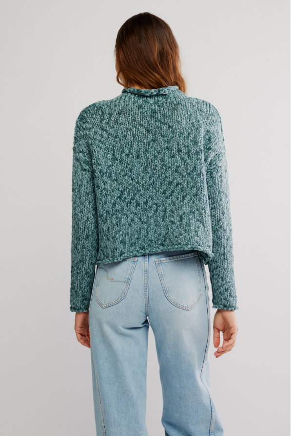 Person wearing a blue green sweater knit and light blue jeans